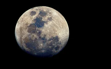 Luna Mineral - Fotografía astronómica detallada de la Luna llena contra un cielo negro, mostrando sus cráteres y sutiles colores minerales.