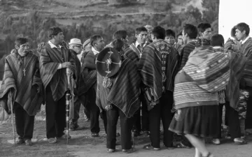 Domingo de Pascua - Fotografía en blanco y negro de un grupo de personas con vestimenta tradicional y ponchos reunidos al aire libre en Chinchero, Perú.