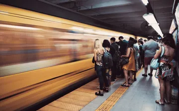 En un tiempo - Fotografía urbana en la estación de Subte Malabia: pasajeros esperando en el andén mientras un tren amarillo pasa a toda velocidad, creando un efecto de barrido en movimiento.